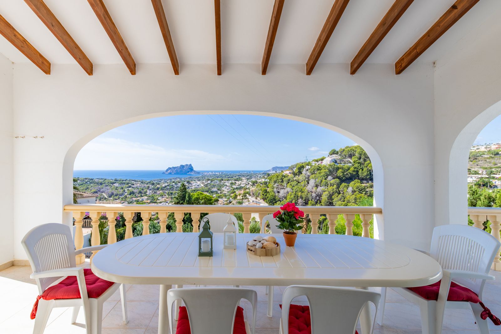 Terrasse couverte avec poutres en bois et arches méditerranéennes, offrant une vue panoramique sur la mer et le Peñón de Ifach depuis l'espace repas.