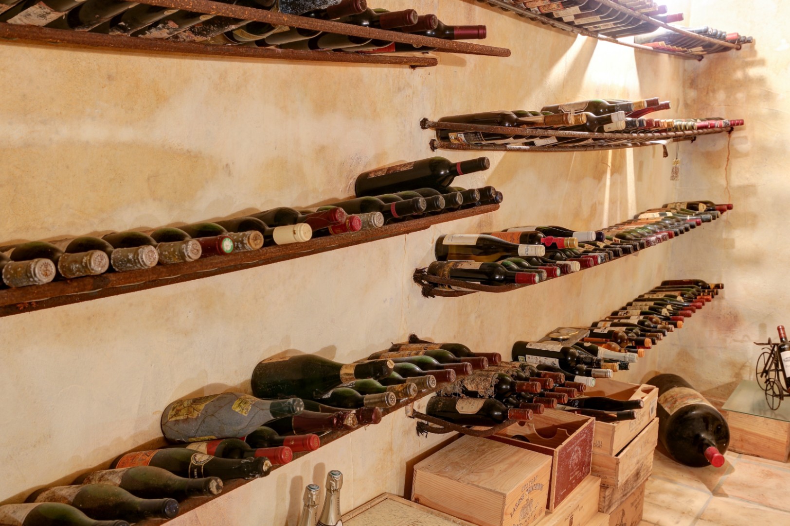 Cave à vin rustique avec murs à texture vieillie, supports à bouteilles en métal et caisses en bois authentiques pour la conservation du vin.