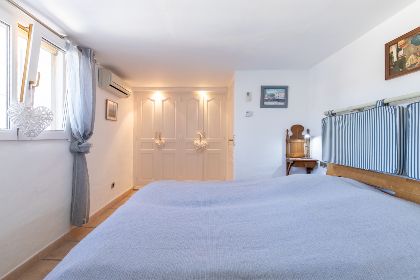 Chambre avec placards intégrés blancs, éclairage encastré, climatisation et fenêtres à double vitrage assurant luminosité et confort thermique.
