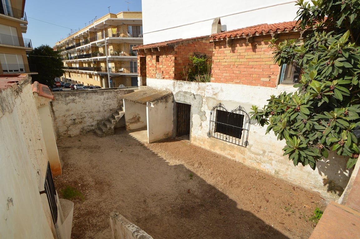 Patio privé clos avec sol en terre, dépendances en briques apparentes et escalier extérieur, situé au cœur de la vieille ville de Jávea.