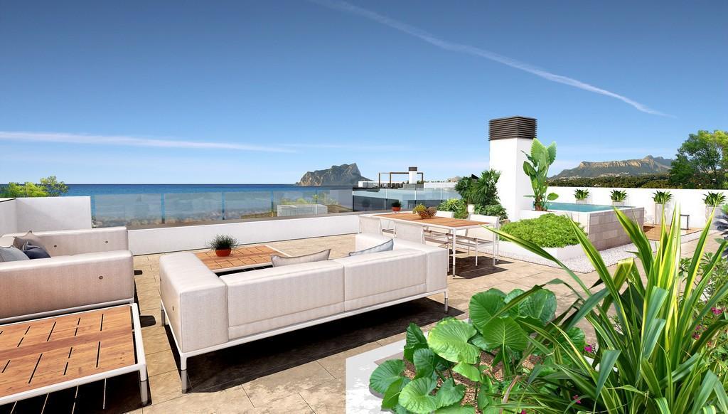 Toit-terrasse avec salon de jardin, espace dînatoire et garde-corps en verre offrant une vue panoramique sur la mer Méditerranée et le Peñón de Ifach.