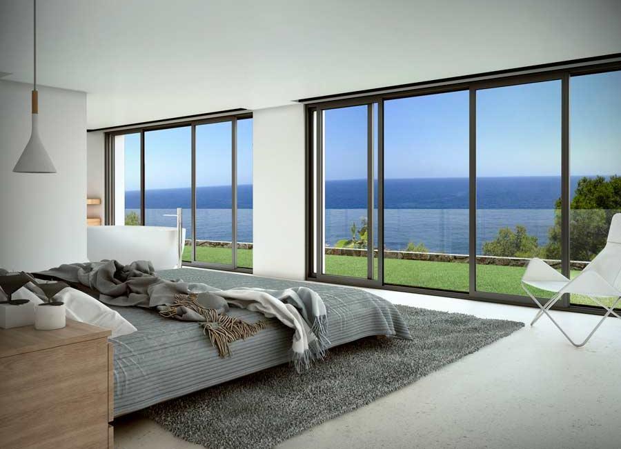 Chambre minimaliste avec baies vitrées coulissantes offrant une vue panoramique sur la mer Méditerranée, agrémentée d'une baignoire îlot et d'un mobilier épuré.