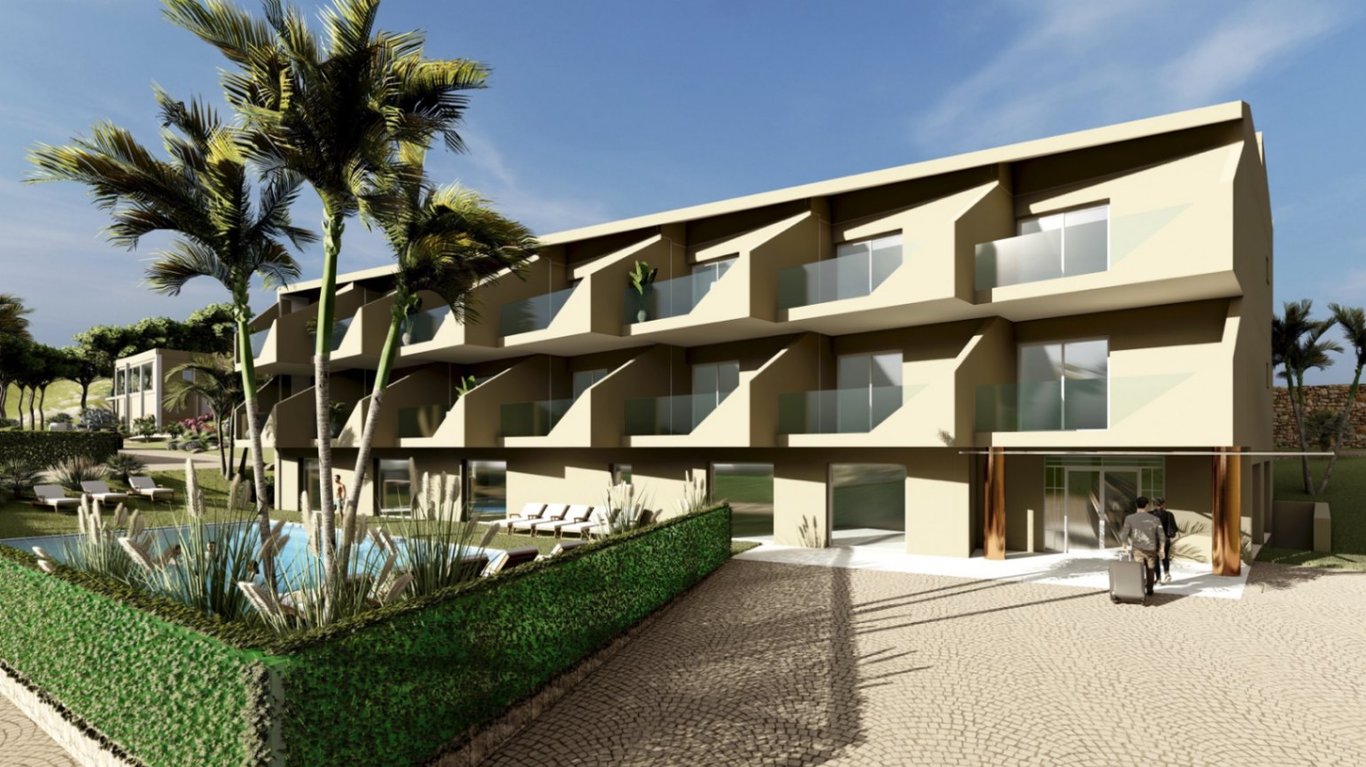 Vue extérieure de l'hôtel boutique sur trois niveaux avec balcons privés vitrés, piscine entourée d'espaces verts et entrée principale pavée.