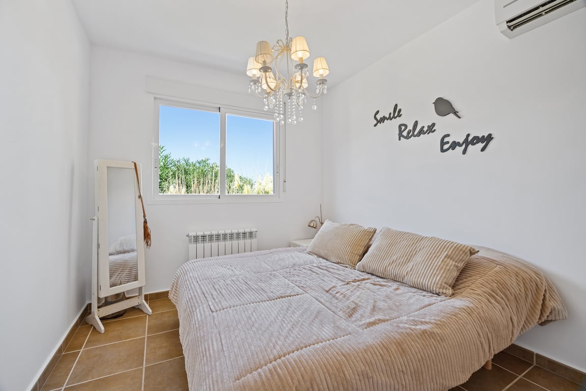 Chambre lumineuse avec sol en grès, climatisation réversible, chauffage central et fenêtre à double vitrage offrant une vue sur la végétation.