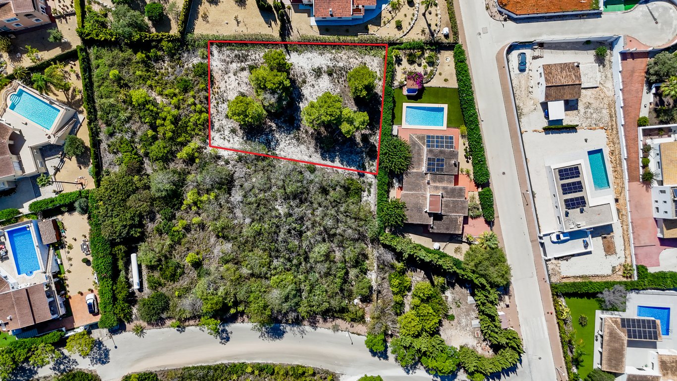 Vue aérienne de la villa avec panneaux solaires et piscine, mettant en évidence le terrain constructible adjacent délimité en rouge.