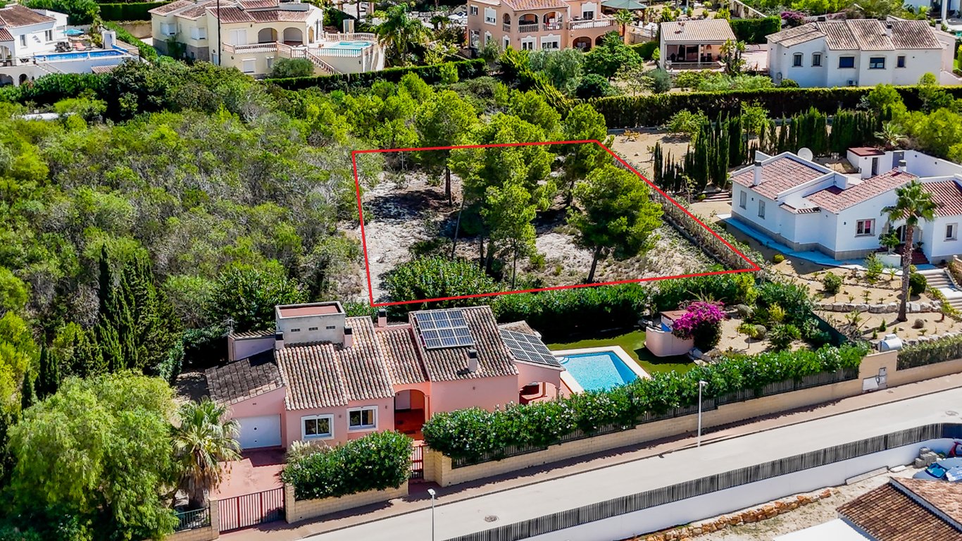 Vue aérienne de la villa avec panneaux solaires et piscine, montrant le terrain urbain constructible adjacent délimité en rouge.