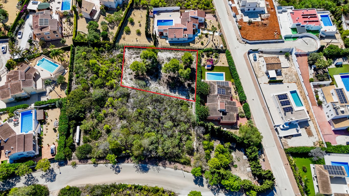 Vue aérienne mettant en évidence le terrain urbain constructible délimité en rouge, jouxtant la villa principale avec sa piscine et ses panneaux solaires.