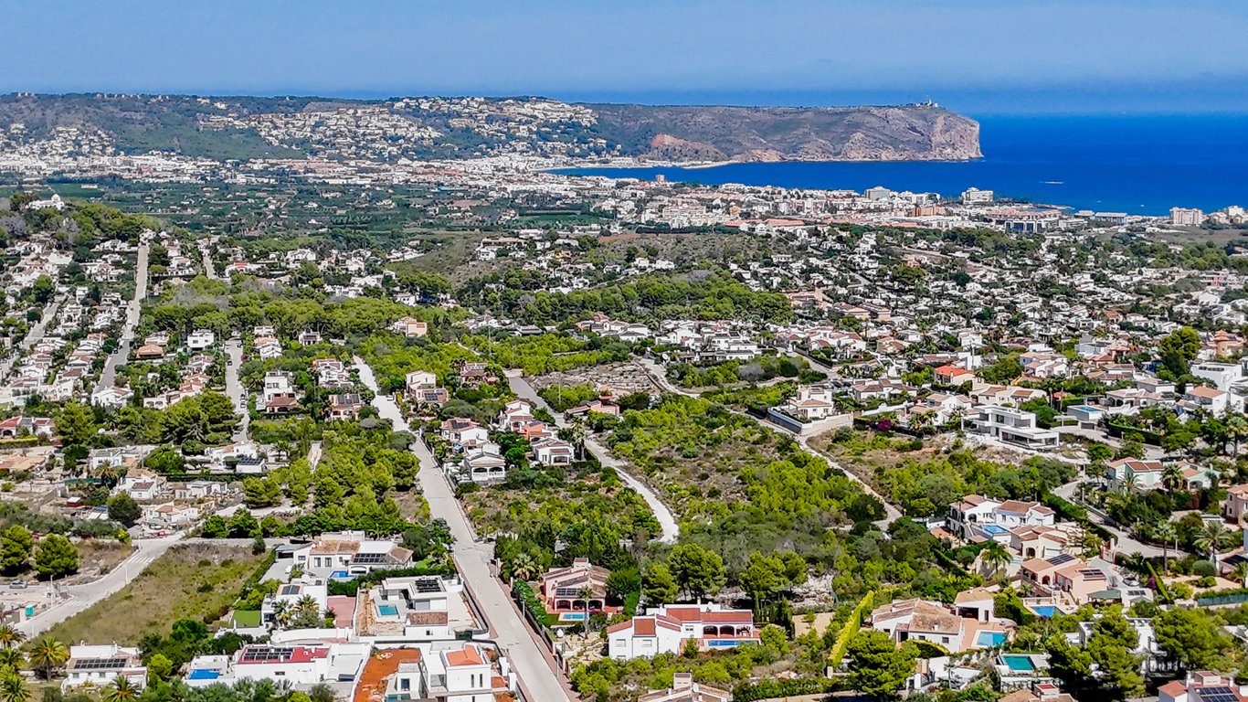 Vue aérienne panoramique de Jávea révélant la proximité de la mer Méditerranée, du Cap San Antonio et des quartiers résidentiels entourés de végétation.