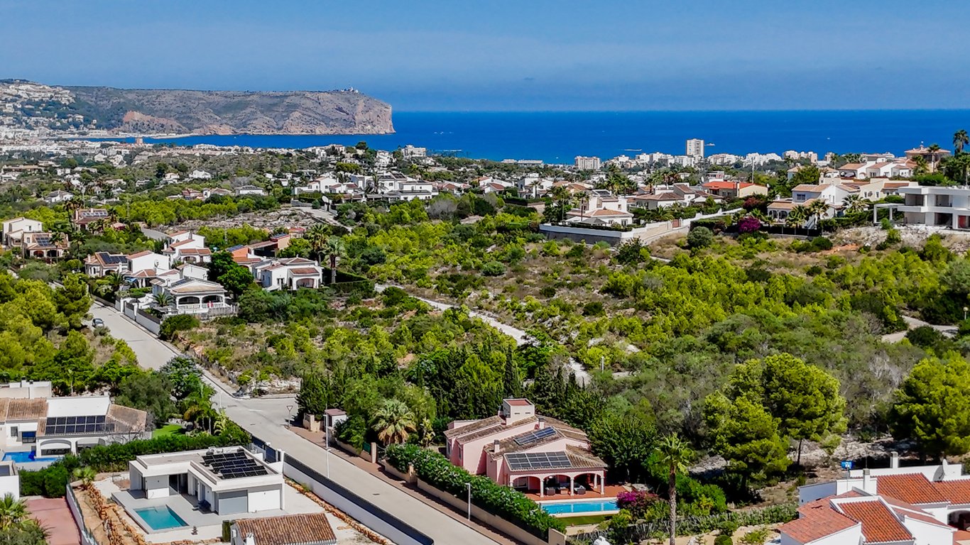 Vue aérienne panoramique de la villa avec ses panneaux solaires, située dans un quartier résidentiel calme offrant une vue imprenable sur la mer et le littoral.