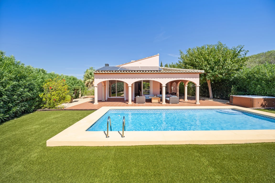 Vue extérieure avec piscine en mosaïque, naya à arcades, panneaux solaires en toiture, gazon synthétique et un jacuzzi extérieur privé.