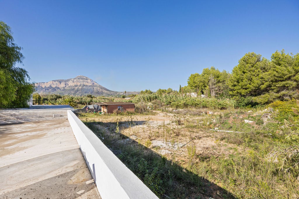 Vue panoramique sur le mont Montgó depuis une terrasse surélevée en béton, surplombant un terrain plat entouré de végétation méditerranéenne.