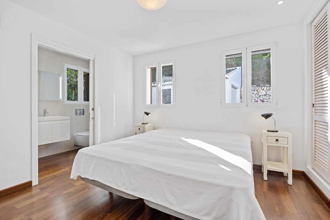 Chambre lumineuse avec parquet au sol, salle de bains attenante modernisée et fenêtres à double vitrage offrant une belle luminosité naturelle.