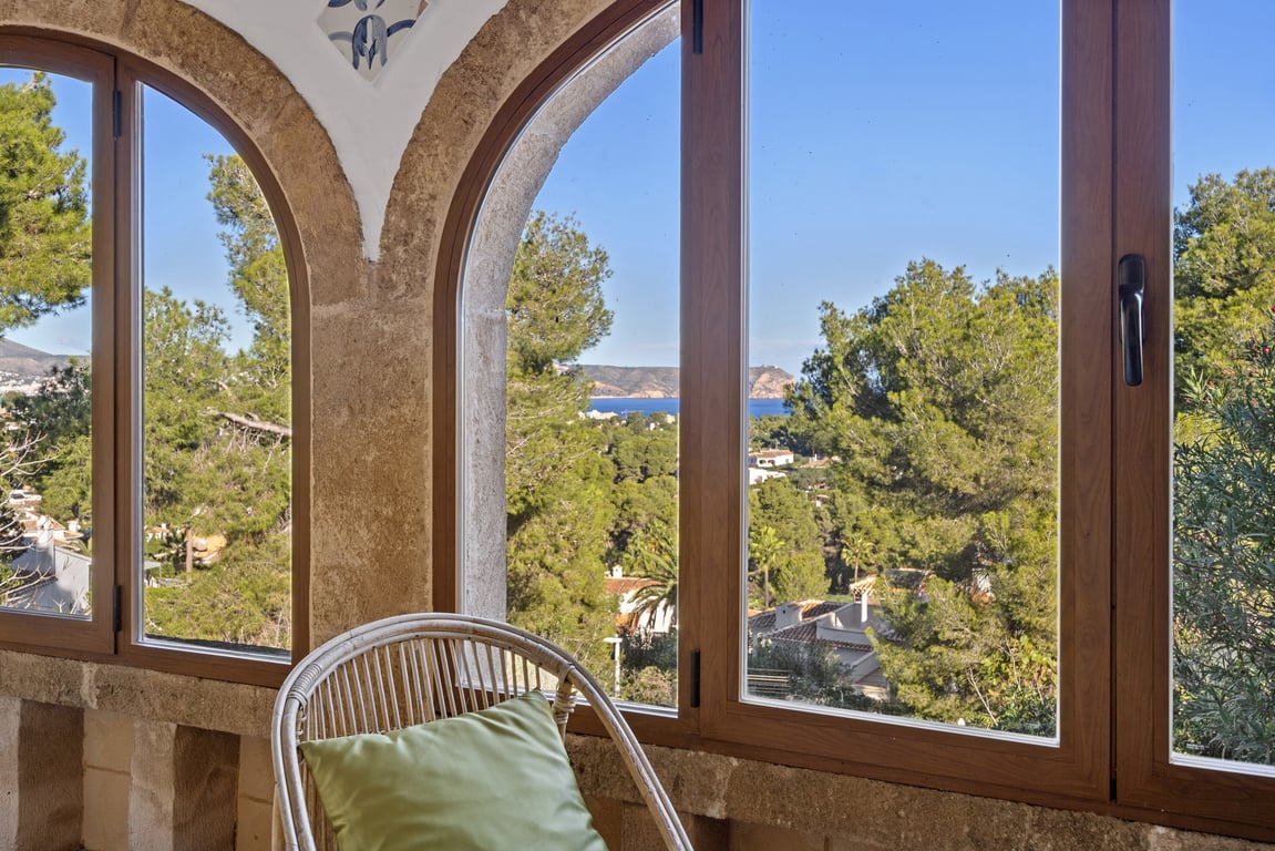 Naya vitrée avec arches en pierre Tosca d'origine, offrant une vue panoramique sur la mer Méditerranée et les paysages verdoyants de Jávea.