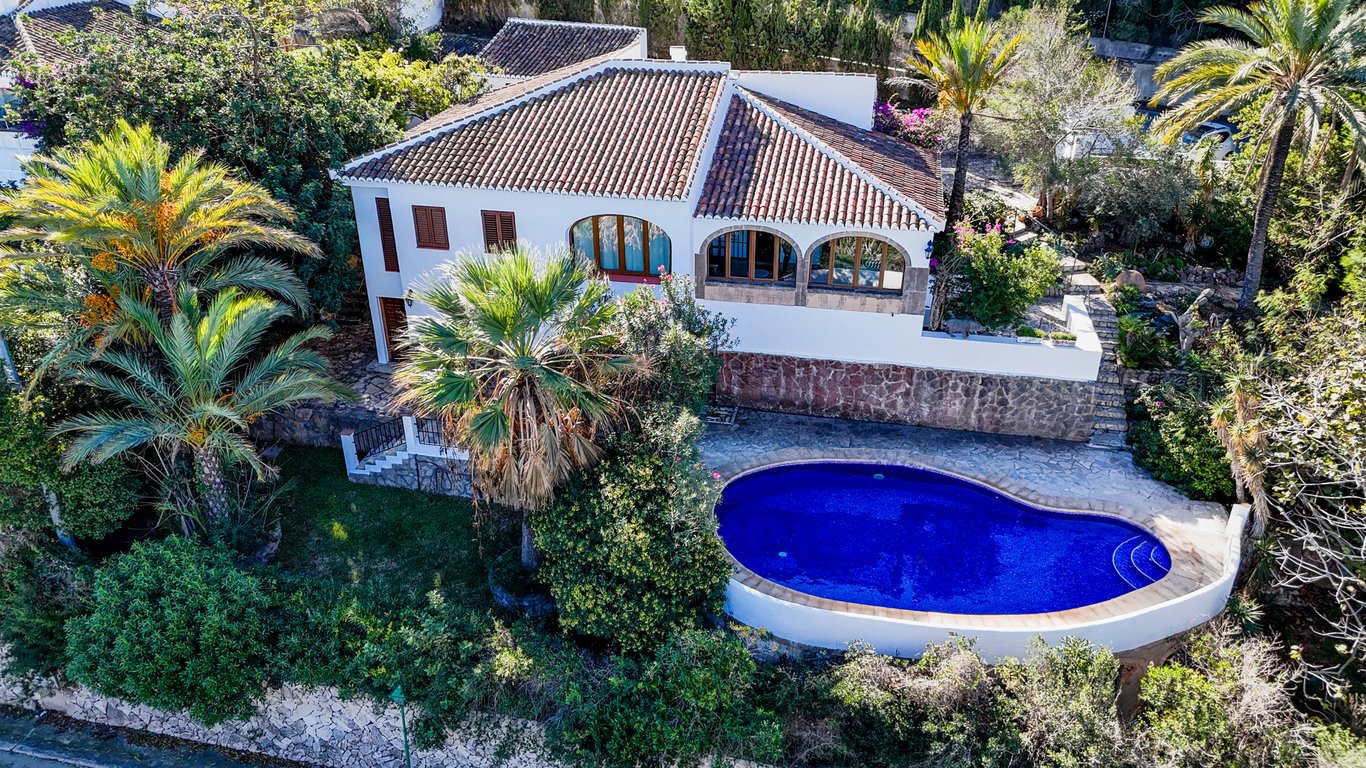 Vue aérienne de la villa avec sa piscine privée de forme ovale, entourée de palmiers et d'une naya traditionnelle aux arches en pierre de Tosca.