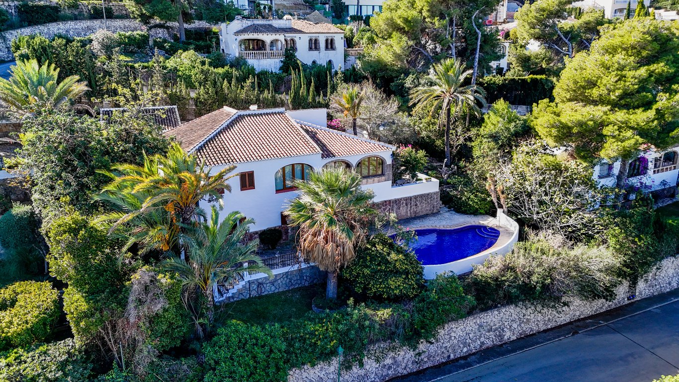 Vue aérienne de la villa traditionnelle avec sa piscine privée, sa naya à arcades et son jardin méditerranéen luxuriant bordé de murs en pierre.
