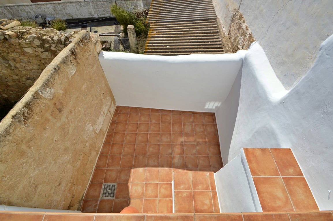 Terrasse privée avec revêtement de sol en terre cuite, murs blanchis à la chaux et un mur latéral en pierre d'origine conservant le cachet authentique.