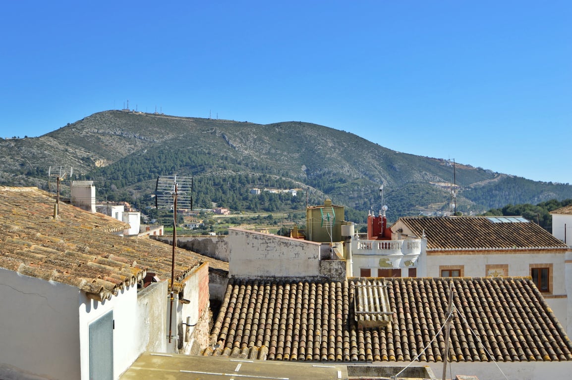 Vue panoramique sur les montagnes et les toits traditionnels en terre cuite depuis la terrasse sur le toit de la propriété.