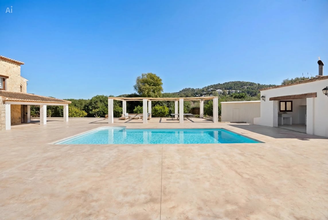 Piscine de 5x10 mètres avec vaste terrasse, pergola en bois et cuisine d'été, offrant une vue dégagée sur les collines environnantes sous un ciel azur.