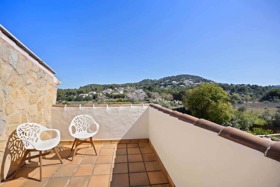 Terrasse privée à l'étage avec sol en terre cuite, offrant une vue panoramique sur les collines verdoyantes et le paysage naturel de Jávea.