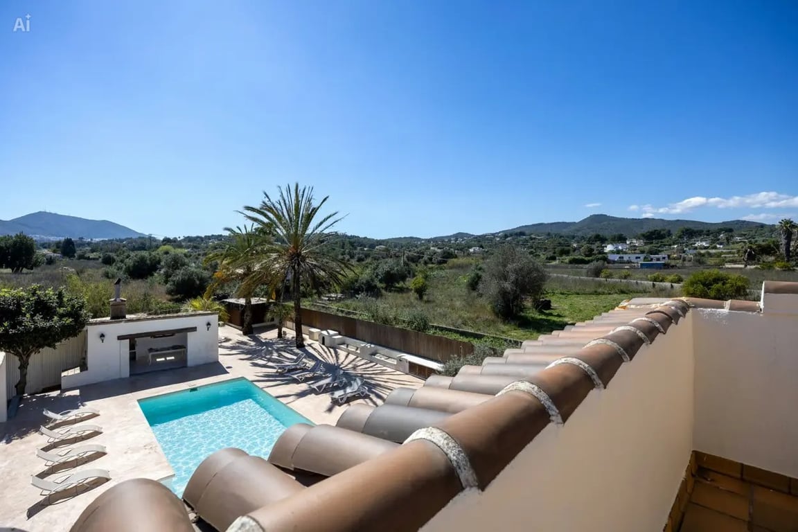Vue surélevée depuis l'étage supérieur sur la piscine de 5x10m, la cuisine d'été et le panorama verdoyant s'étendant jusqu'aux montagnes.