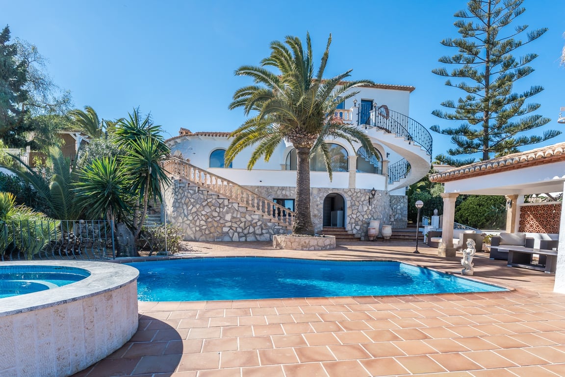 Vue extérieure avec piscine, jacuzzi circulaire et façade en pierre apparente. Un escalier en colimaçon relie les terrasses au cœur d'un jardin méditerranéen.