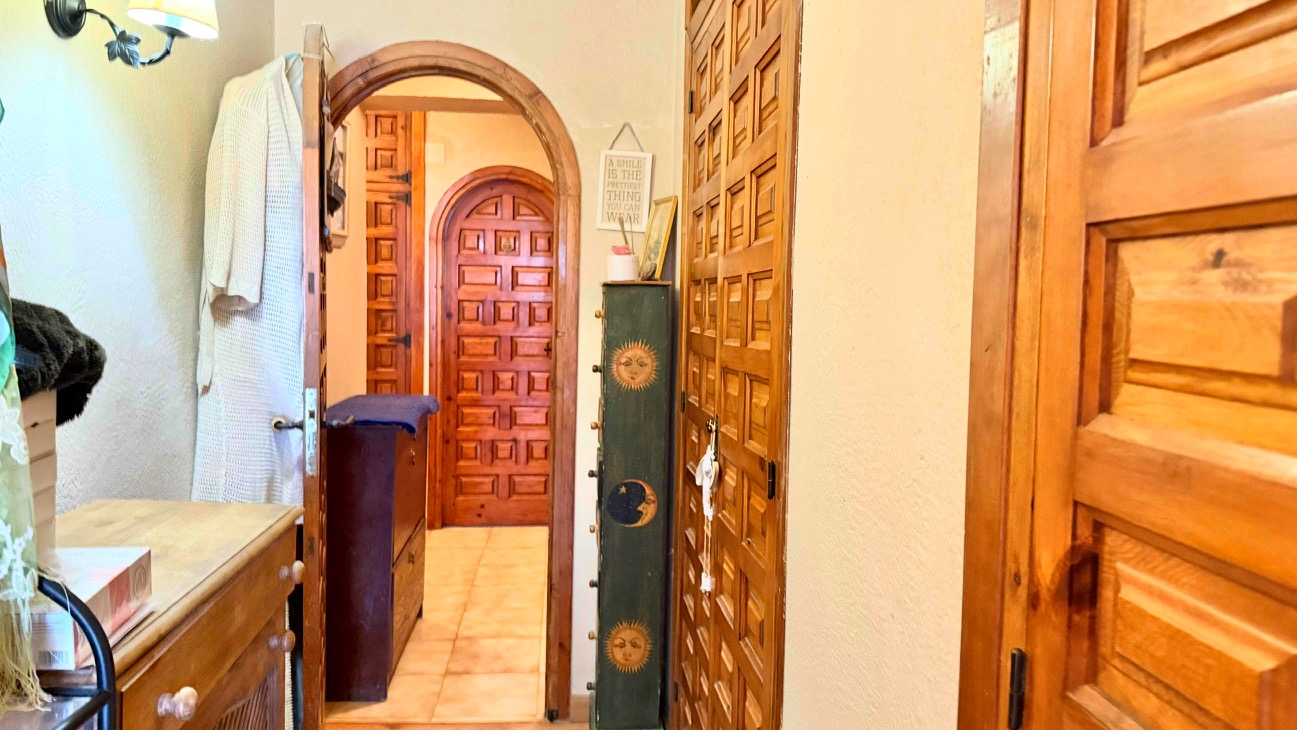 Couloir avec des arches en bois traditionnelles et des portes en bois massif sculpté, complété par un sol en carrelage clair.