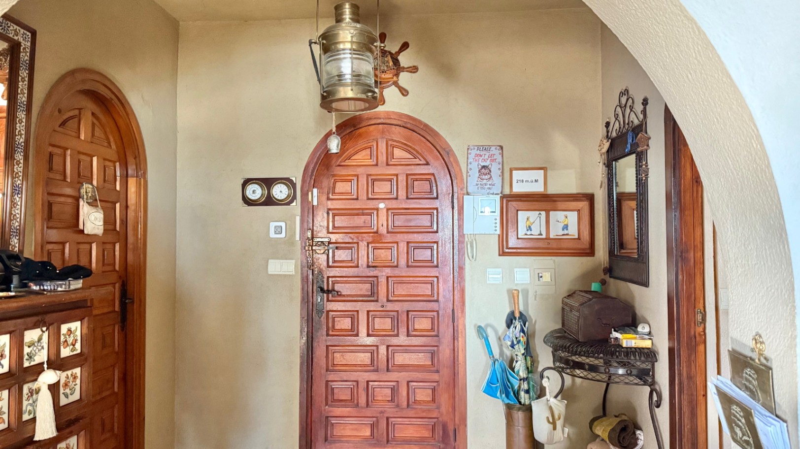 Hall d'entrée avec portes en bois massif voûtées, décoration sur le thème nautique et une suspension lanterne en laiton.