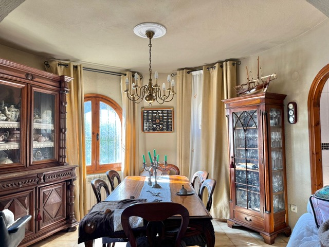 Salle à manger de style classique avec buffets en bois massif, lustre d'époque et une fenêtre cintrée apportant une luminosité naturelle.