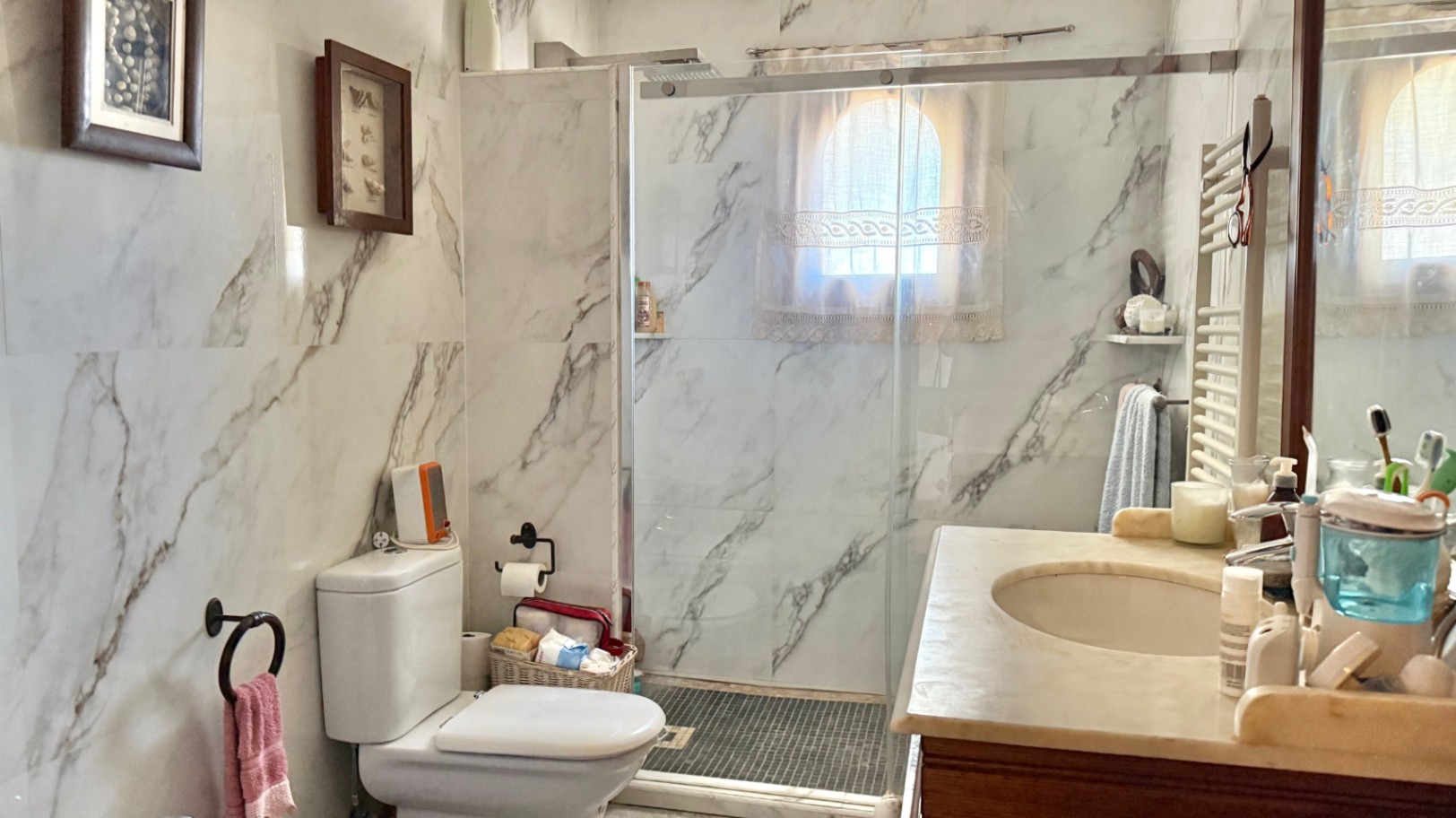 Salle de bain avec murs en carrelage effet marbre, douche à l'italienne avec paroi vitrée et meuble vasque en pierre naturelle.