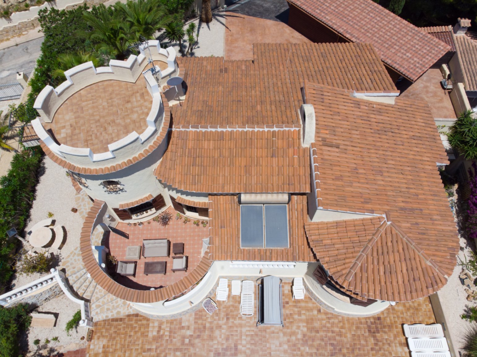 Vue aérienne de la villa révélant son architecture méditerranéenne, sa tour crénelée, ses panneaux solaires et ses vastes terrasses en terre cuite.