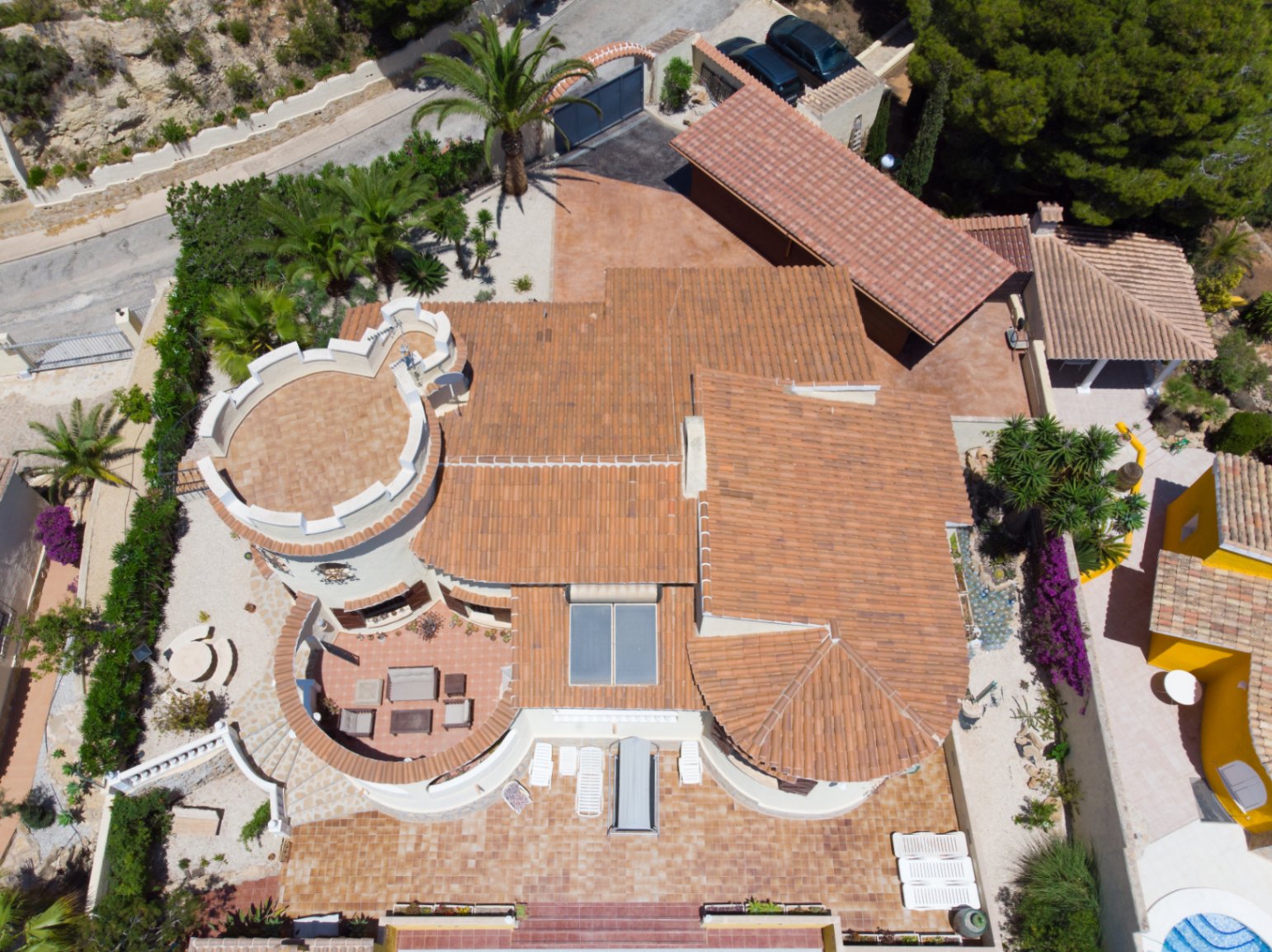 Vue aérienne de la villa soulignant son architecture méditerranéenne, sa tour unique, ses toits en terre cuite, ses panneaux solaires et ses vastes terrasses aménagées.