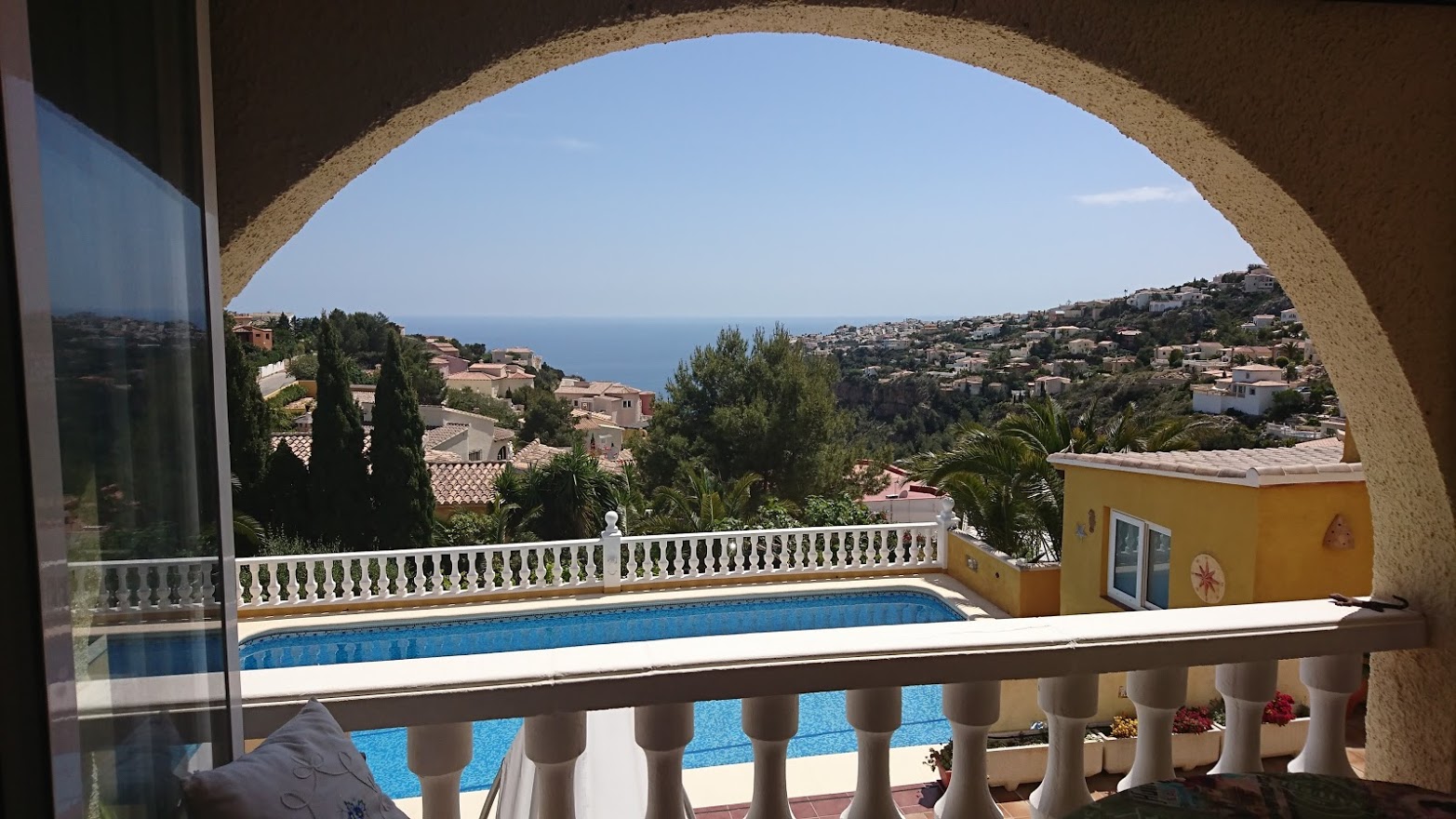 Vue panoramique sur la mer Méditerranée encadrée par une arche, surplombant la piscine privée et le paysage côtier de Benitachell.