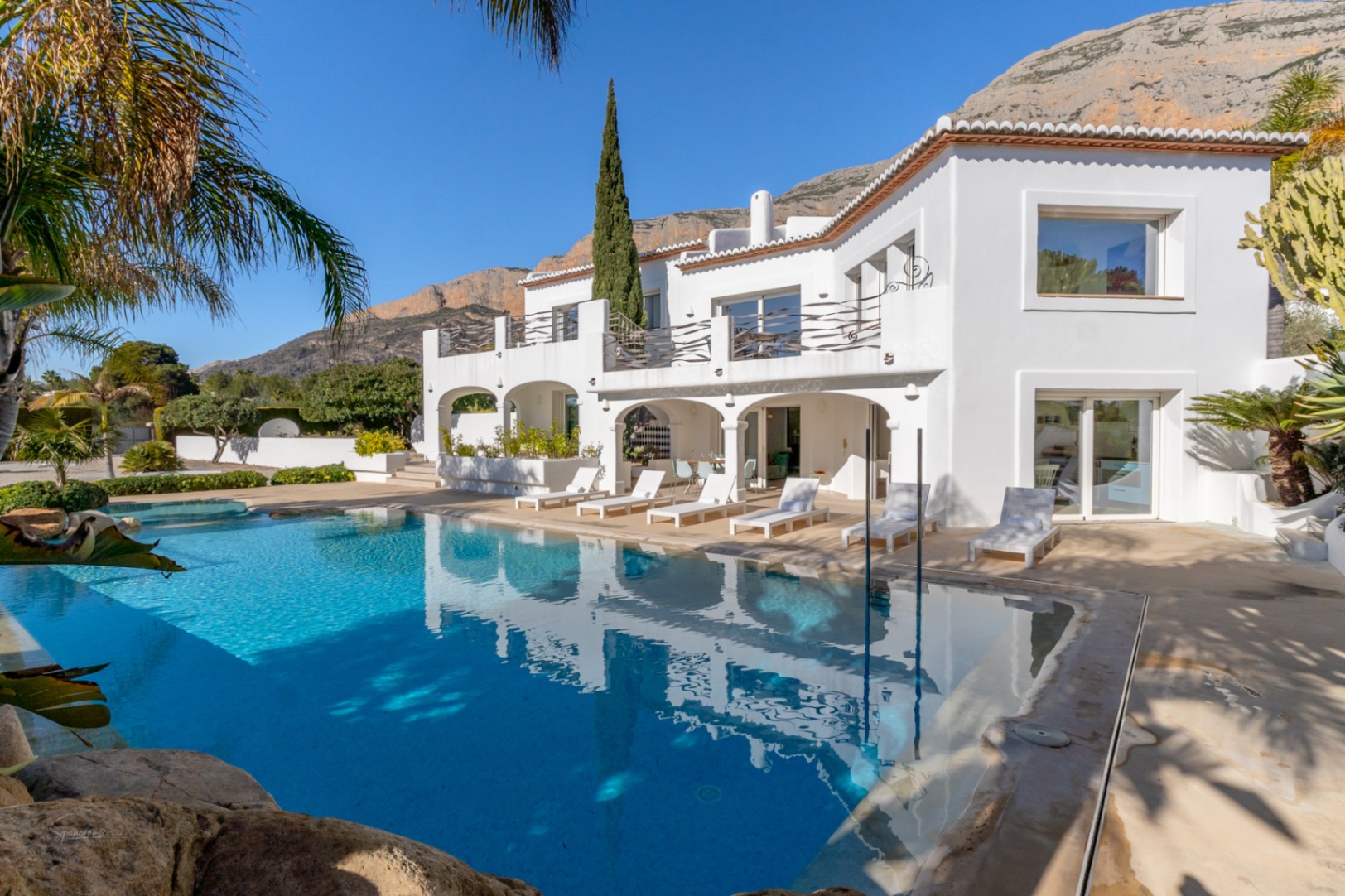Façade extérieure de la villa style Ibiza avec piscine de 70m², naya voûtée et terrasse à l'étage face à la majestueuse montagne Montgó.