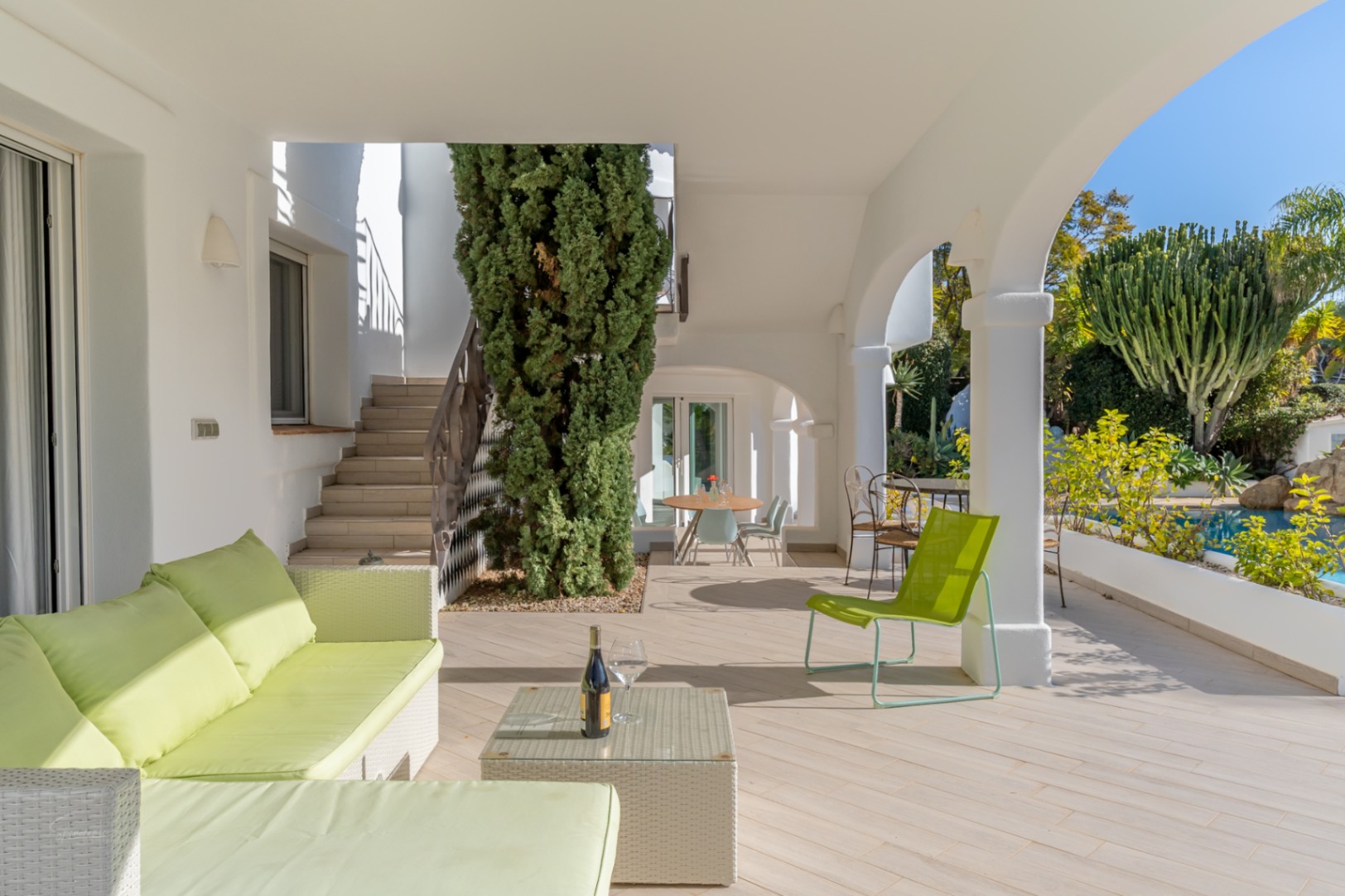 Naya couverte avec arches blanches, mobilier de jardin vert citron et vue imprenable sur la piscine et le jardin méditerranéen.