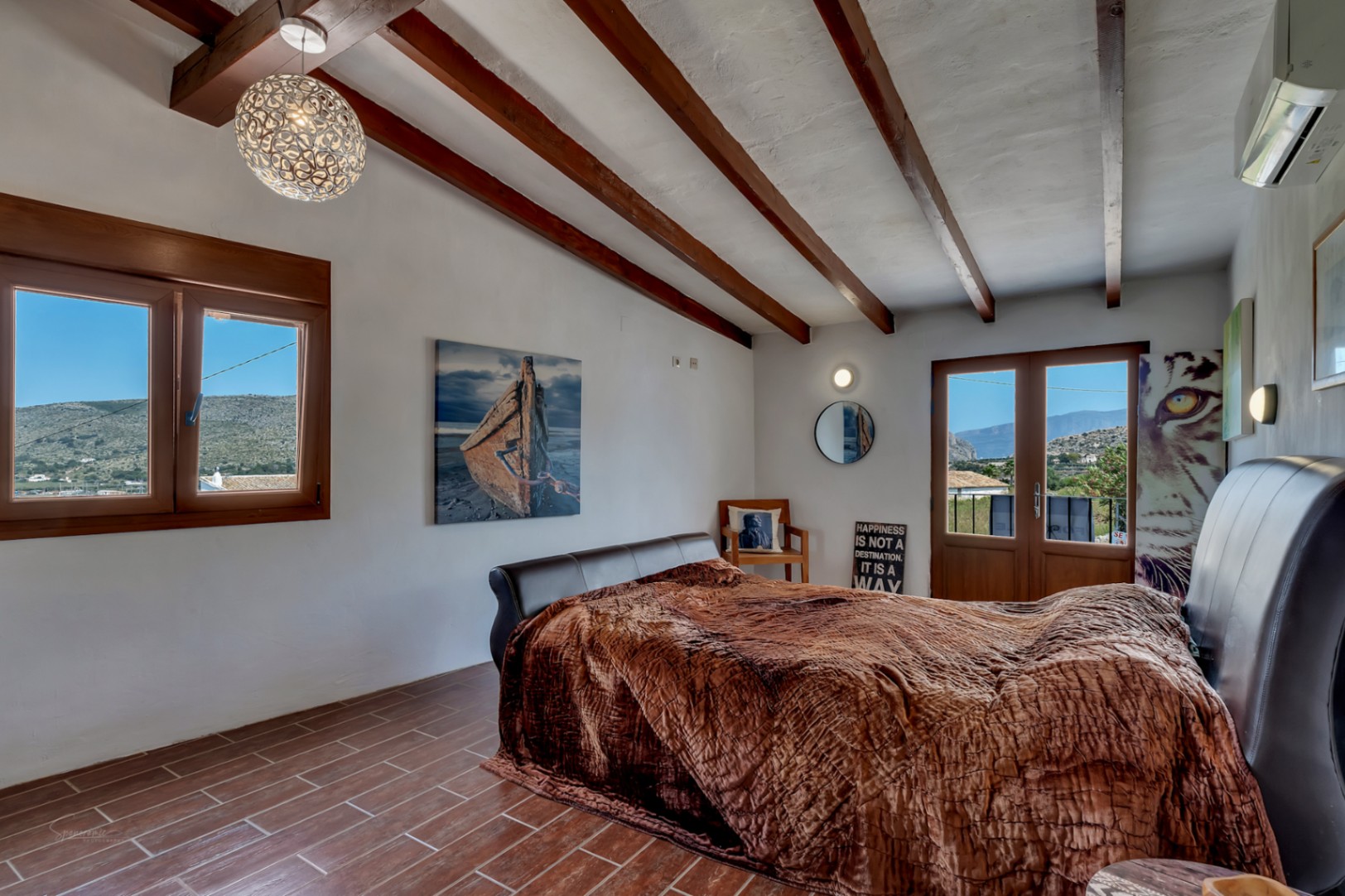 Chambre rustique avec poutres en bois, sol carrelé et vue sur la montagne.
