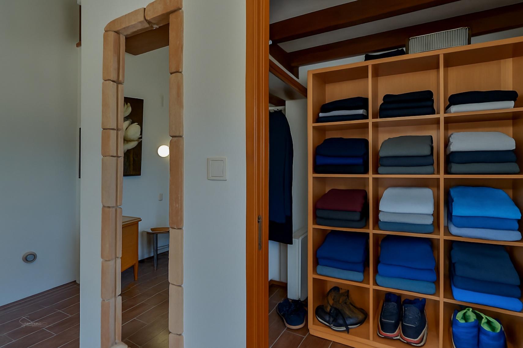 Détail d'un dressing avec des étagères en bois clair et une porte avec un cadre en pierre à Teulada.