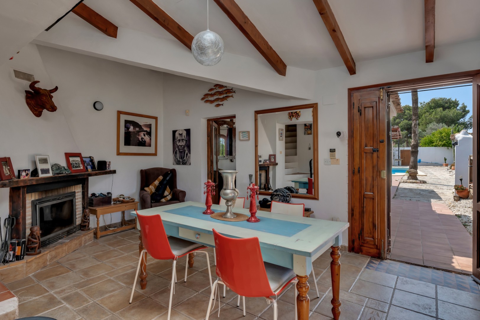 Salle à manger rustique avec cheminée, poutres apparentes et accès au jardin avec piscine à Teulada.