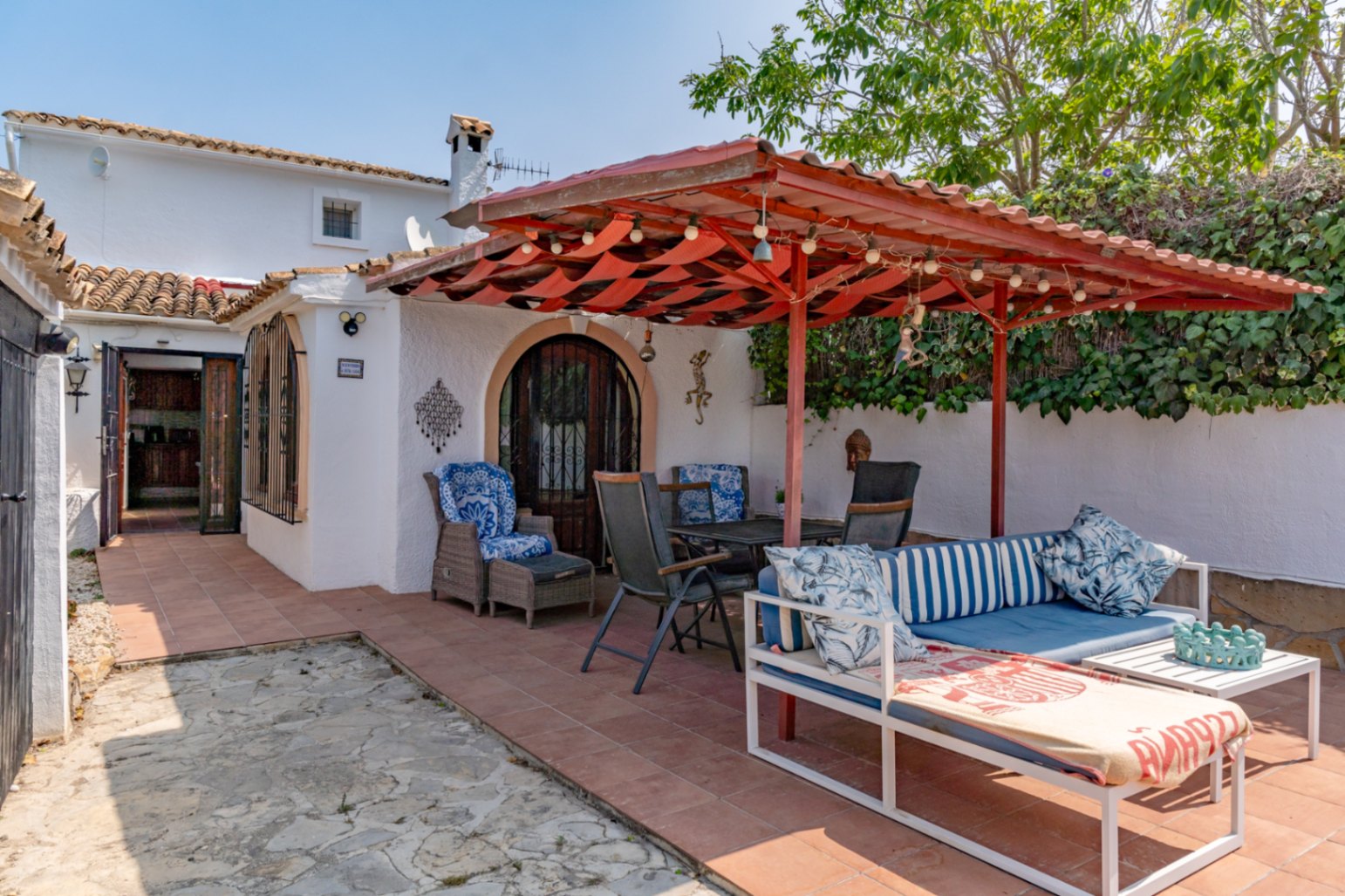 Terrasse couverte avec auvent rouge, mobilier de jardin et accès à la maison de campagne à Teulada.