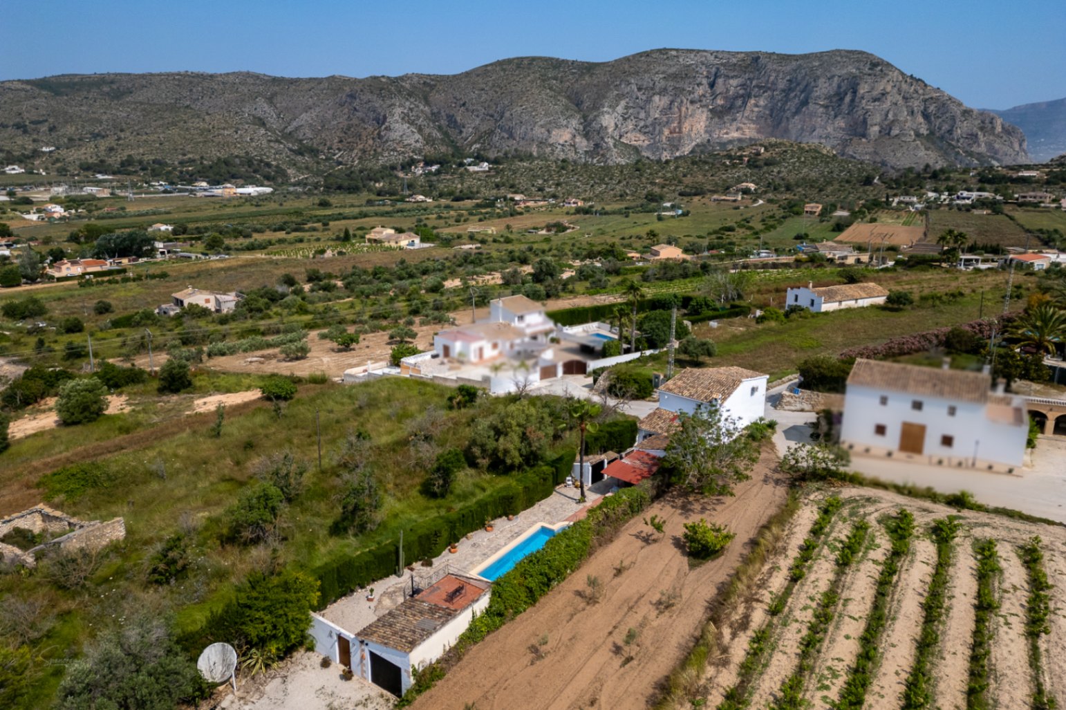 Vue aérienne du domaine à Teulada avec piscine allongée, jardin arboré et vue sur la montagne.