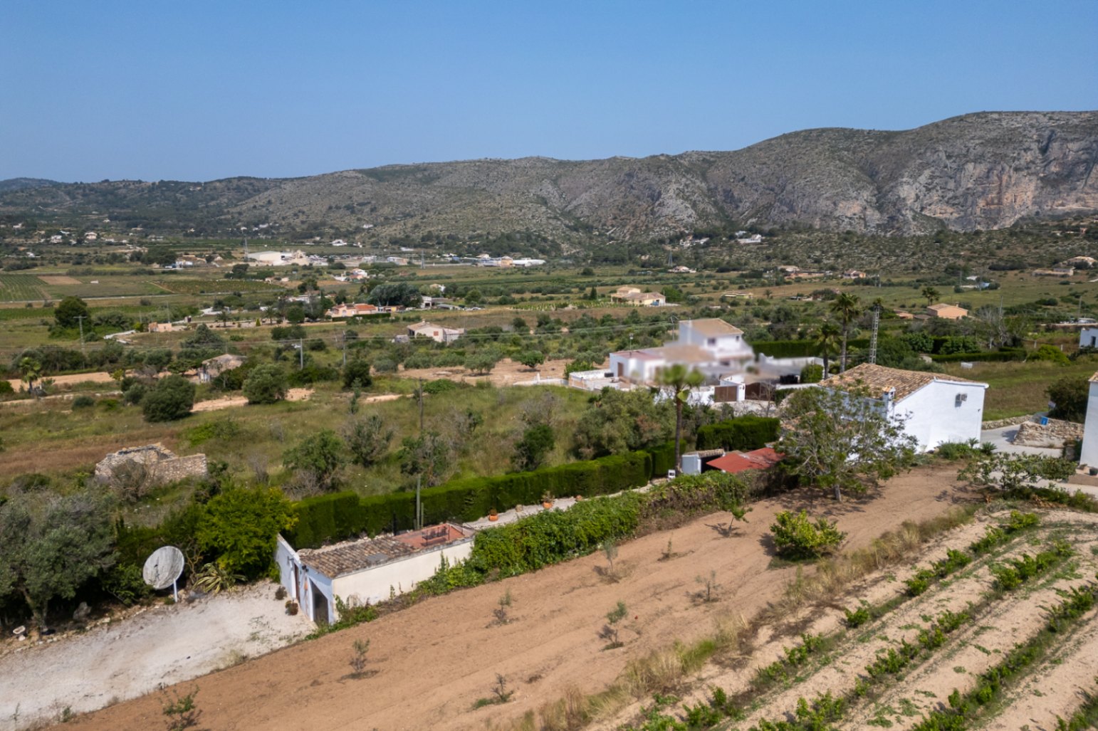 Vue aérienne du domaine de Teulada avec terrain cultivé et bâtiment blanc.
