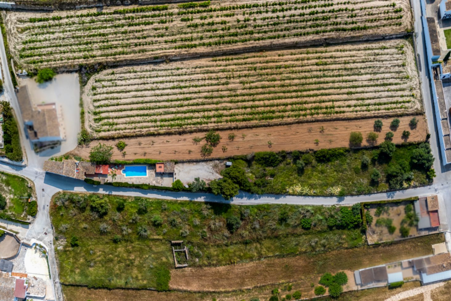 Vue aérienne d'une finca rustique avec piscine à Teulada, entourée de terres agricoles et de végétation méditerranéenne.