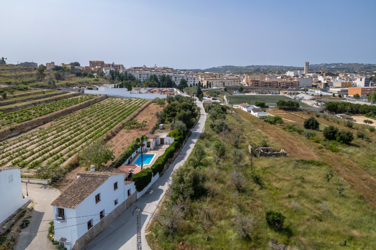 Vue aérienne d'une maison de campagne avec piscine à Teulada, entourée de vignes et de végétation méditerranéenne.