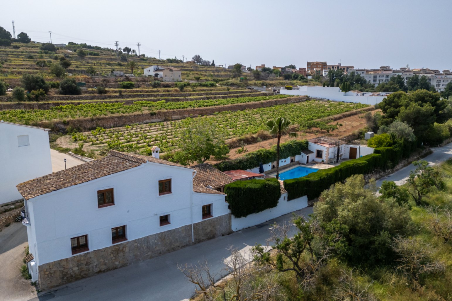 Vue aérienne d'une maison de campagne blanche avec piscine, entourée de vignes à Teulada, Costa Blanca.