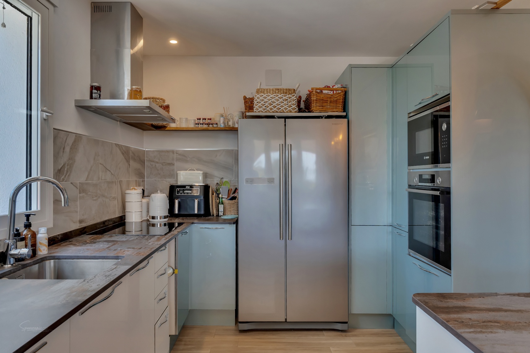 Cuisine avec comptoirs en pierre, électroménagers en acier inoxydable et armoires bleu pâle.