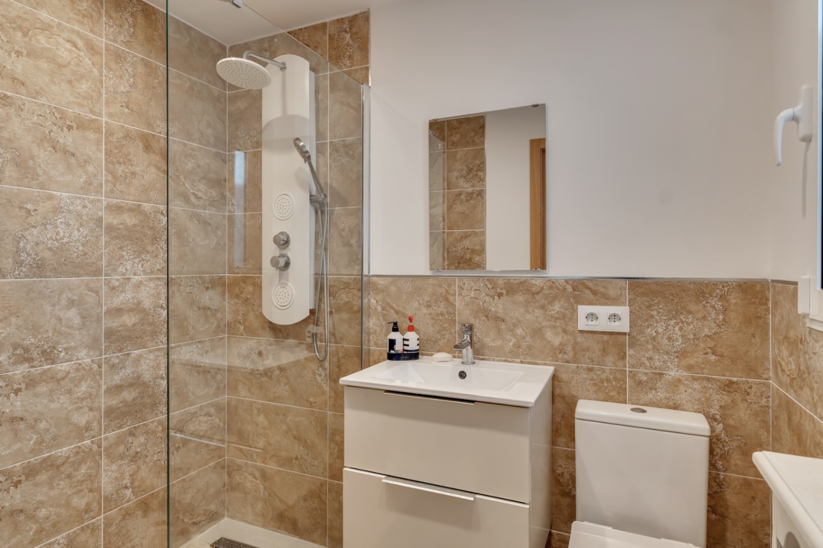 Détail de salle de bain avec douche moderne et carrelage céramique tons terre.
