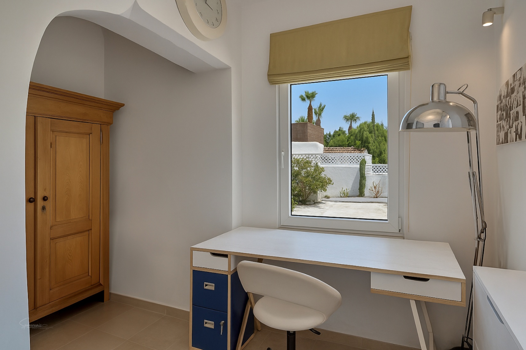 Détail du bureau avec bureau blanc, armoire en bois et vue sur l'extérieur.