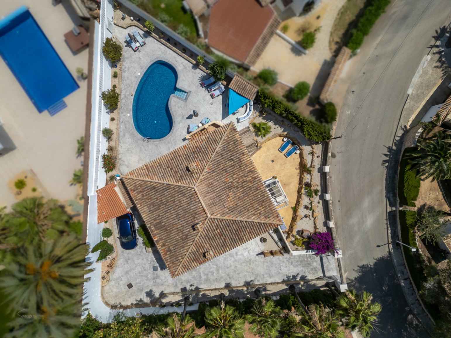 Vue aérienne d'une villa avec piscine, terrasse et toit en tuiles rouges. Parking privé visible.