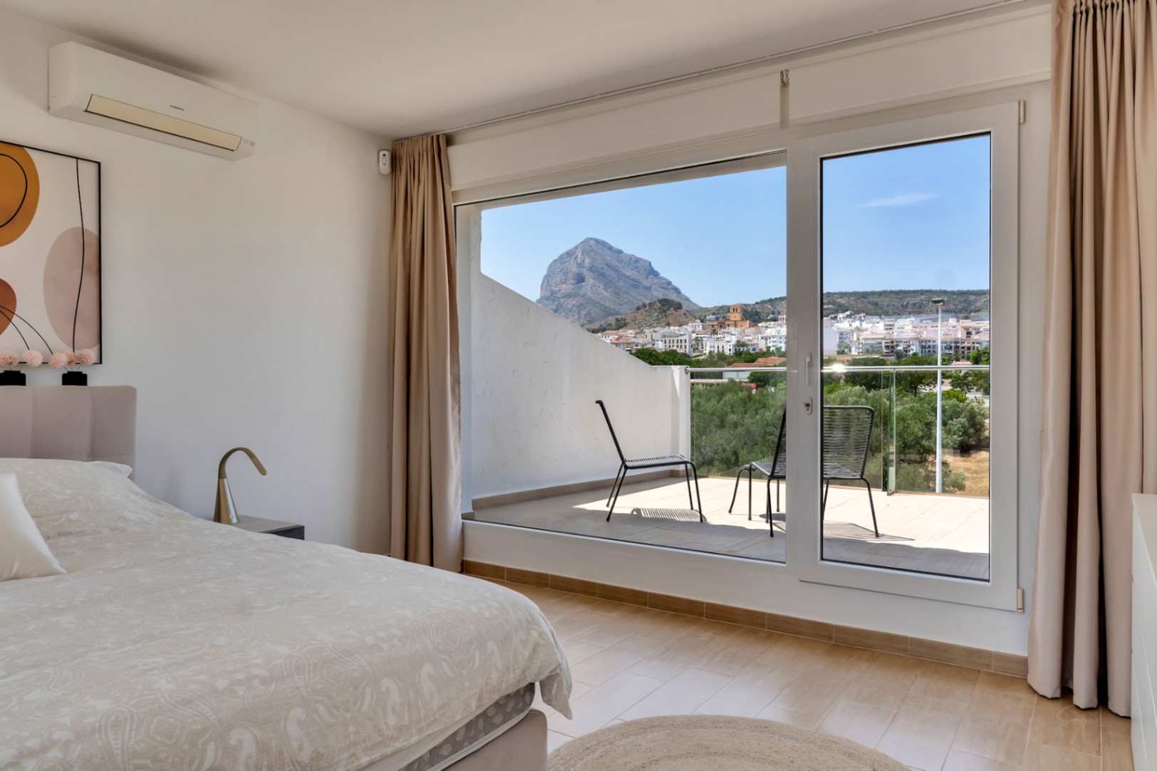 Chambre principale avec terrasse privée offrant une vue panoramique sur le Montgó. Équipée de la climatisation et de grandes baies vitrées pour une luminosité optimale.