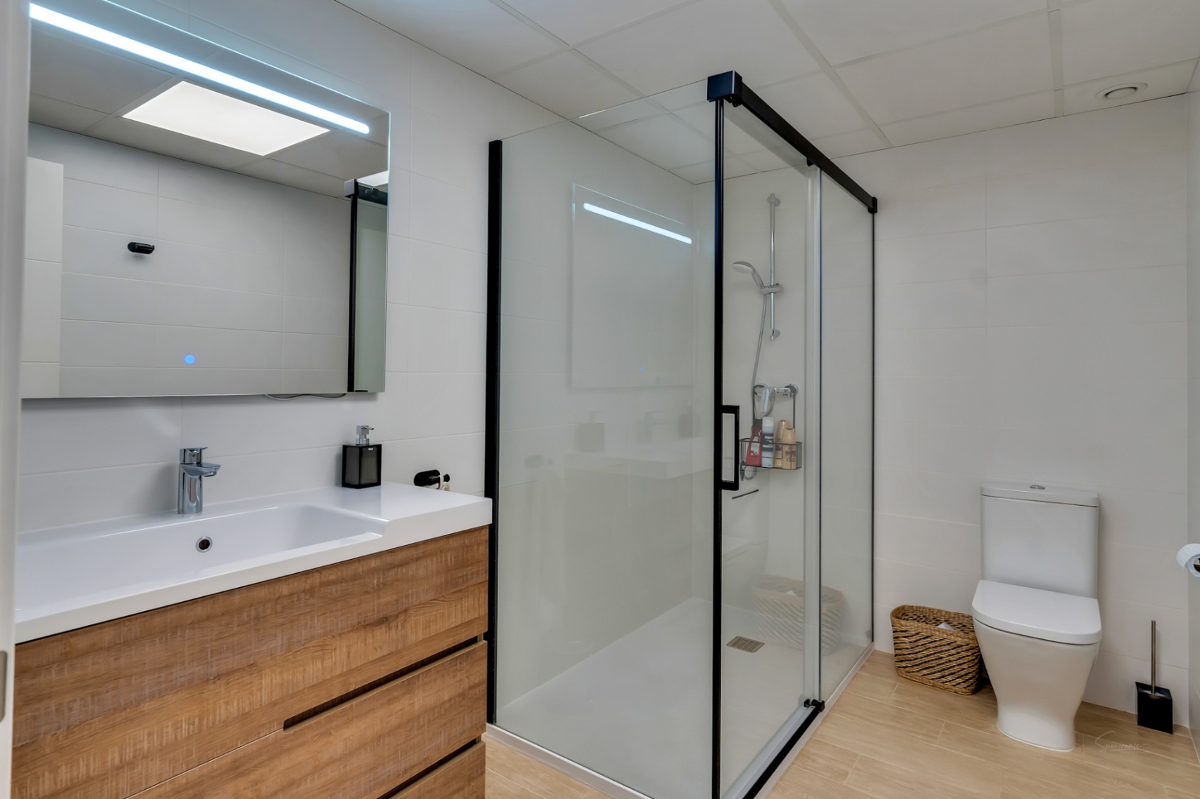Salle de bain moderne avec meuble en bois, miroir à LED et douche à l'italienne avec cadre noir. Le sol en grès cérame effet bois complète le design épuré.