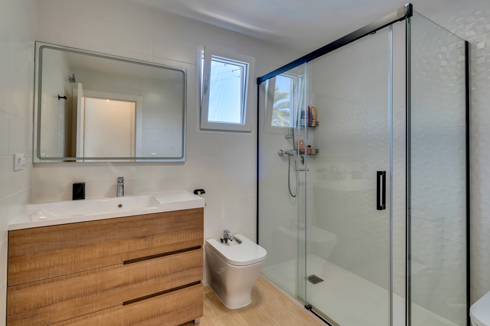 Salle de bains contemporaine avec meuble sous-vasque effet bois, bidet et grande douche à l'italienne avec paroi vitrée à cadre noir et carrelage texturé.
